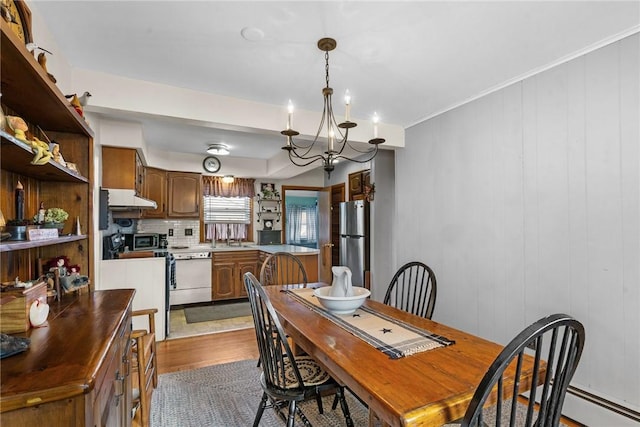 dining space with a baseboard heating unit, an inviting chandelier, dark wood-style flooring, and ornamental molding