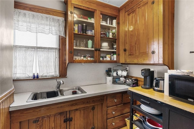 kitchen featuring light countertops, brown cabinets, black microwave, and a sink