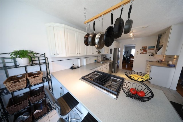 kitchen featuring a sink, light countertops, appliances with stainless steel finishes, white cabinetry, and a kitchen breakfast bar