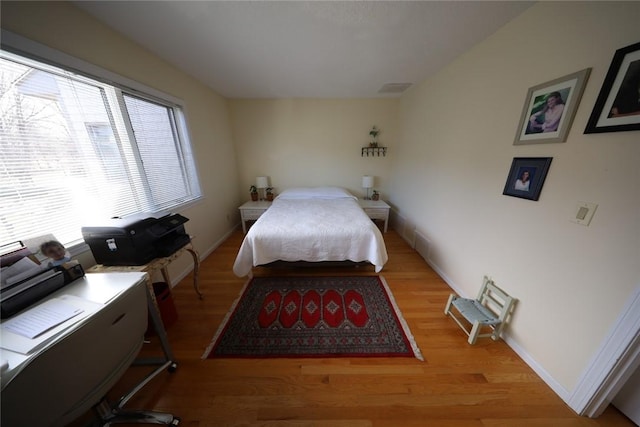 bedroom with visible vents, baseboards, and wood finished floors