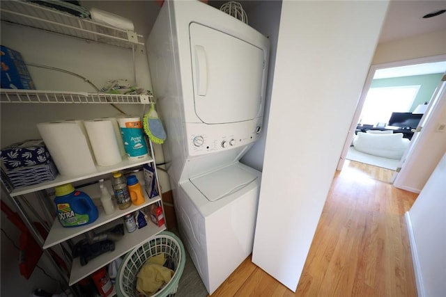 washroom with laundry area, stacked washer and clothes dryer, and wood finished floors