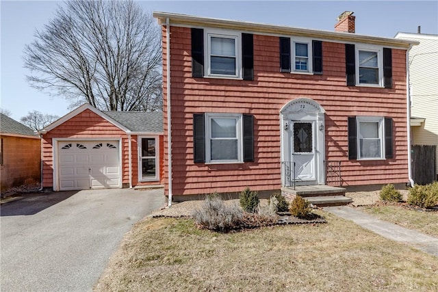 colonial inspired home with roof with shingles, a garage, driveway, and a chimney