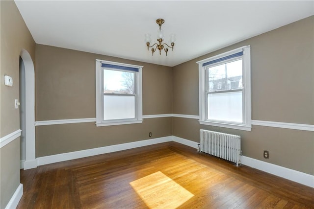 unfurnished room with baseboards, radiator, a healthy amount of sunlight, and wood finished floors