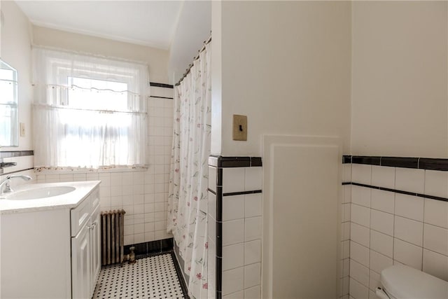 full bathroom with toilet, radiator, tile walls, and vanity