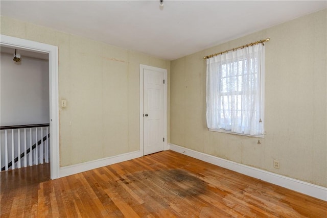 spare room featuring baseboards and wood-type flooring