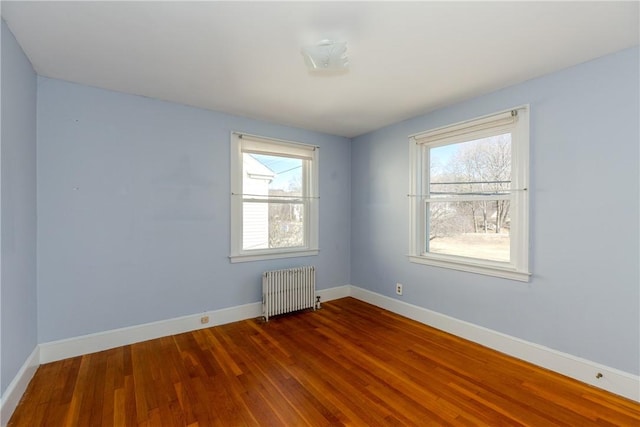 unfurnished room with radiator, wood finished floors, and baseboards