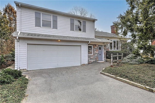 split level home featuring driveway, stone siding, roof with shingles, a garage, and a chimney