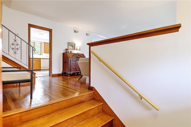 staircase with visible vents, baseboards, and wood finished floors