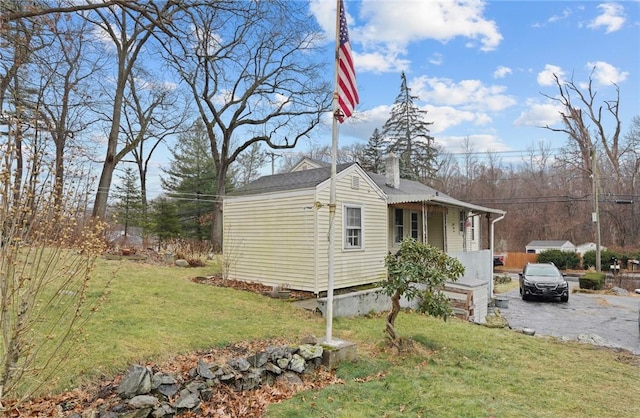 view of side of property with driveway, a chimney, and a yard