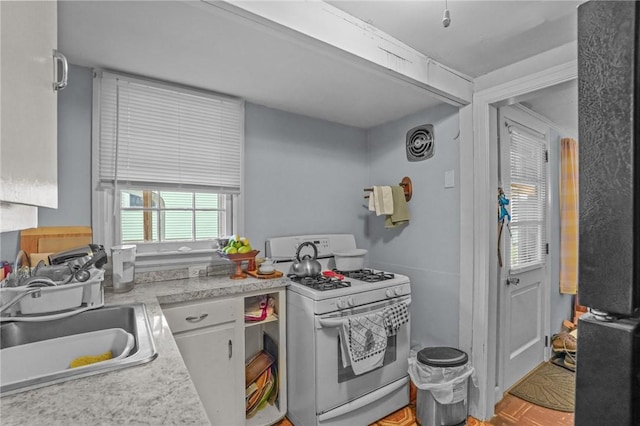 kitchen featuring a sink, visible vents, white range with gas stovetop, and light countertops