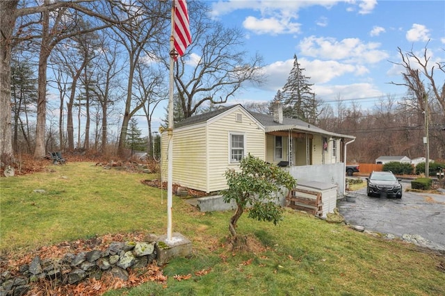 view of side of property with aphalt driveway and a lawn