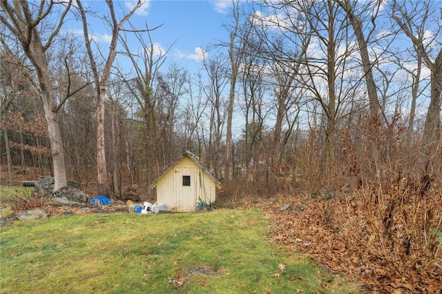 view of yard featuring an outbuilding, a wooded view, and a shed