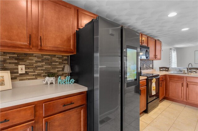 kitchen featuring light countertops, light tile patterned floors, black appliances, and brown cabinets