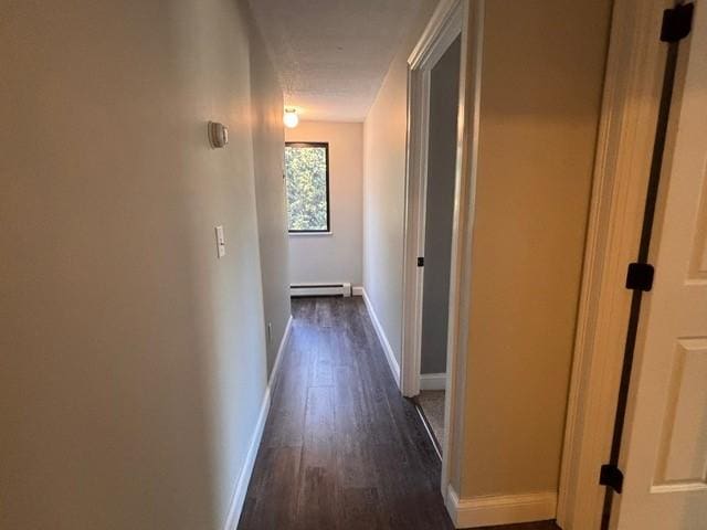 corridor featuring dark wood finished floors, baseboards, and a baseboard radiator