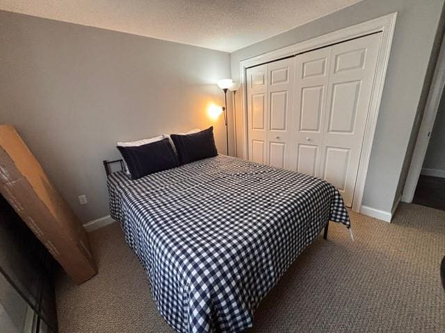 bedroom with a closet, baseboards, a textured ceiling, and carpet flooring