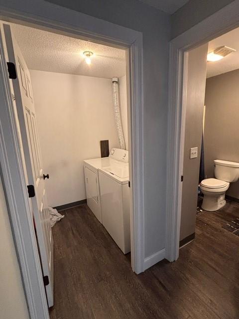 laundry area with baseboards, washing machine and dryer, laundry area, dark wood-style floors, and a textured ceiling