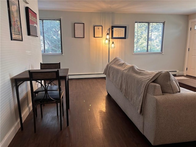 living area featuring a wealth of natural light, baseboard heating, baseboards, and dark wood-style flooring