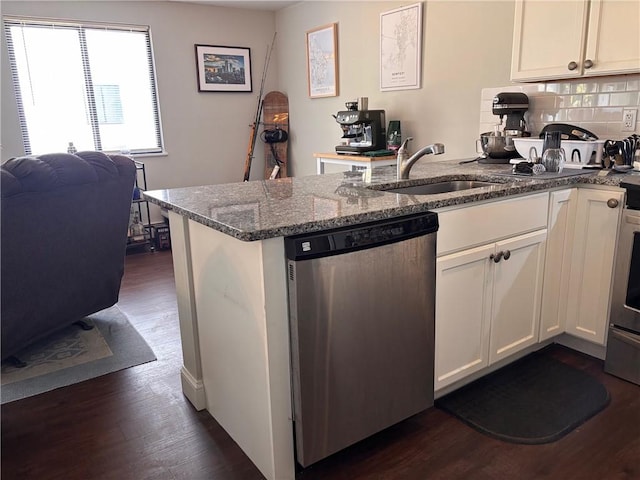 kitchen featuring dark wood-type flooring, a sink, backsplash, stainless steel dishwasher, and a peninsula