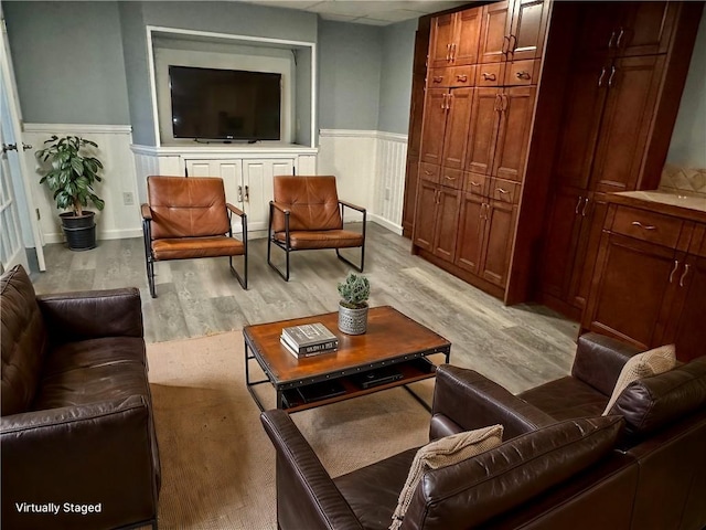 living area with wainscoting and light wood finished floors