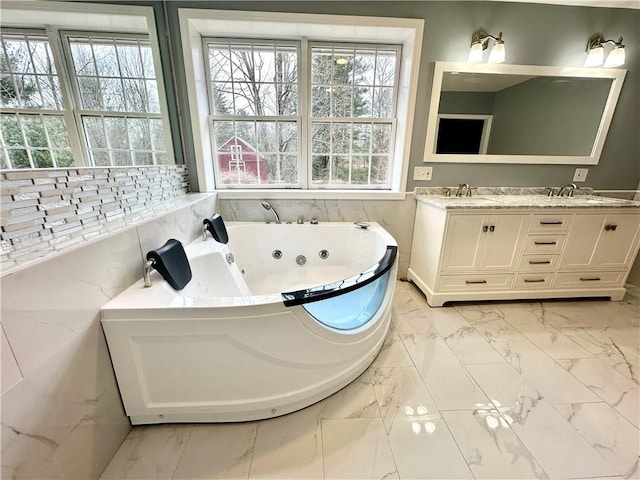 bathroom featuring a sink, marble finish floor, double vanity, and a tub with jets