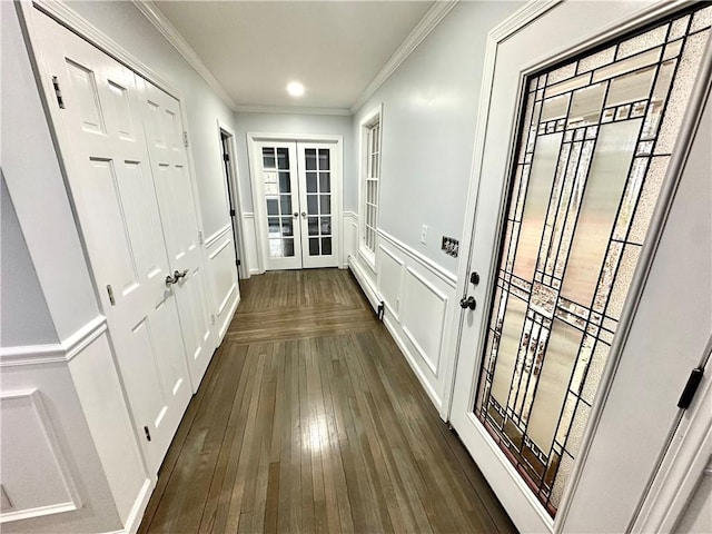 doorway with dark wood-style floors, a wainscoted wall, ornamental molding, french doors, and a decorative wall