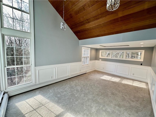 carpeted spare room featuring a notable chandelier, wood ceiling, a wainscoted wall, and a baseboard radiator