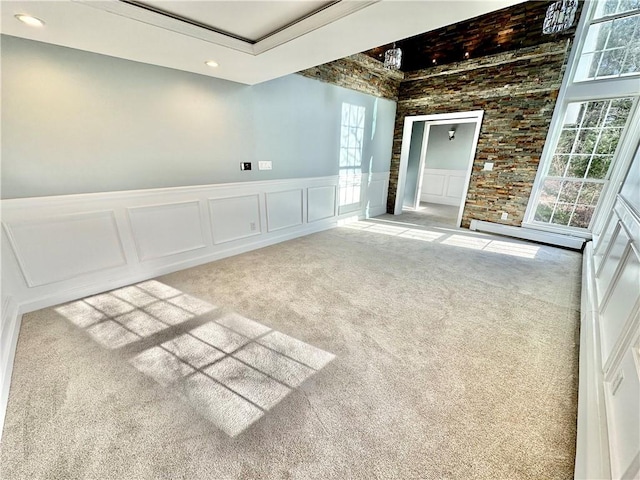 empty room featuring a decorative wall, carpet flooring, recessed lighting, and wainscoting