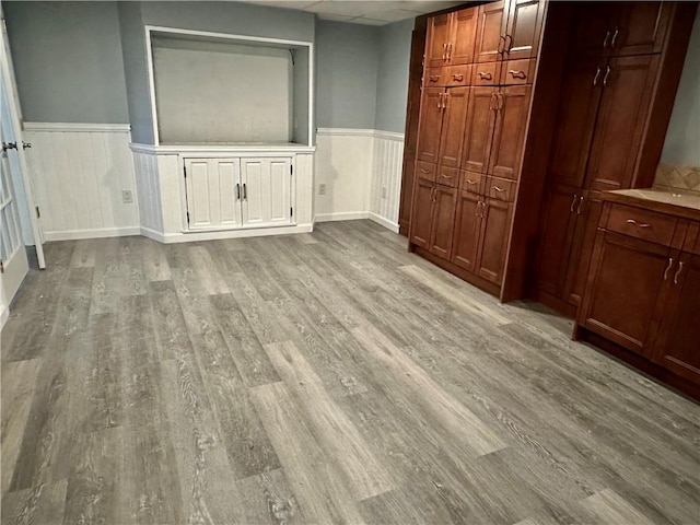 unfurnished bedroom with wood finished floors and wainscoting