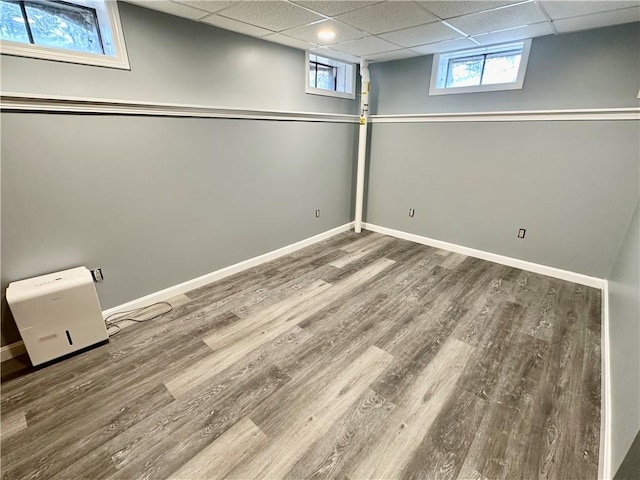 basement with a paneled ceiling, baseboards, and wood finished floors