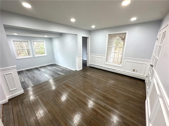 unfurnished room with a baseboard heating unit, recessed lighting, dark wood-style floors, and a healthy amount of sunlight