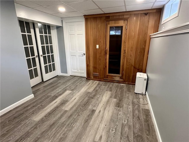 unfurnished room featuring french doors, a paneled ceiling, baseboards, and wood finished floors