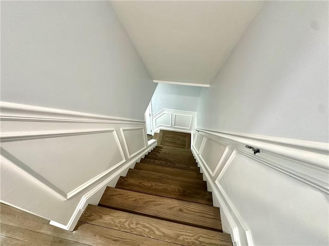 stairway featuring wood finished floors and a decorative wall