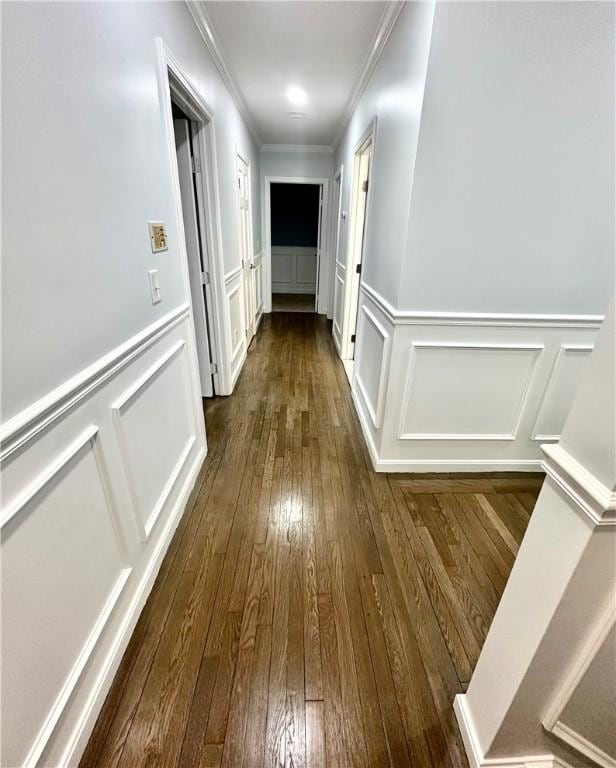 hall featuring a decorative wall, dark wood-style flooring, and crown molding