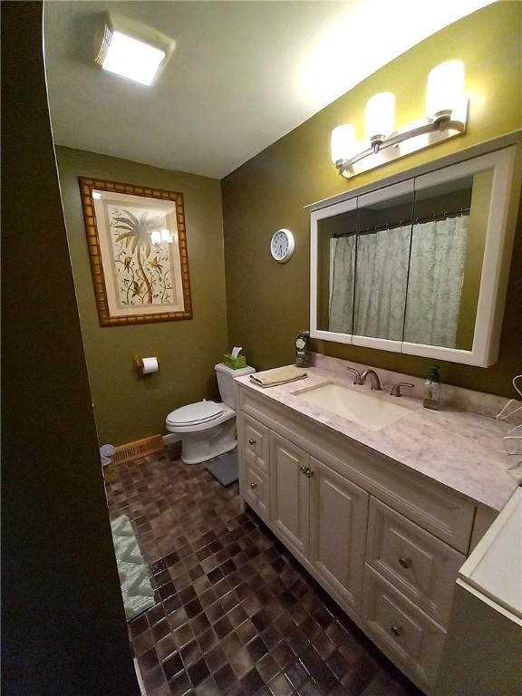 full bathroom with vanity, toilet, and baseboards