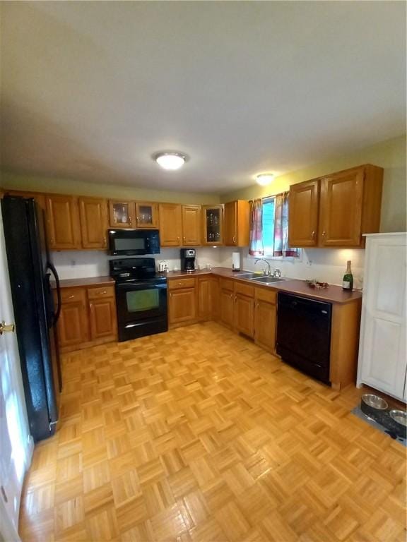 kitchen with a sink, glass insert cabinets, brown cabinets, and black appliances