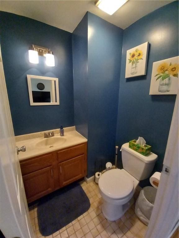 bathroom with toilet, vanity, and tile patterned flooring