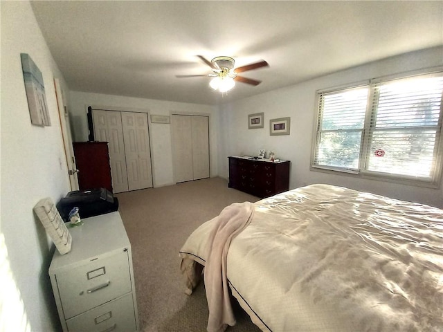 bedroom featuring two closets, carpet, and a ceiling fan