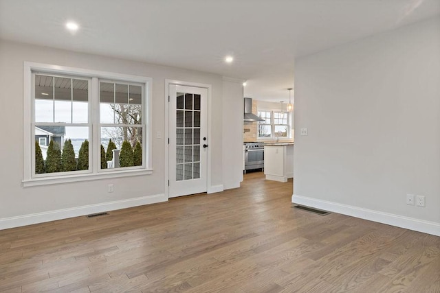 empty room with baseboards, visible vents, light wood finished floors, and a sink