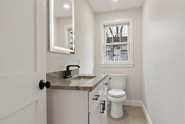 bathroom with baseboards, toilet, and vanity