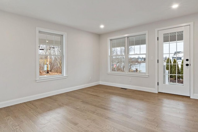 spare room with plenty of natural light, baseboards, light wood-type flooring, and visible vents