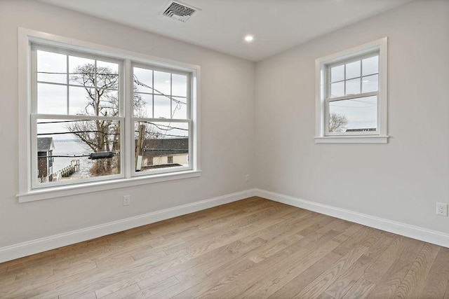 unfurnished room featuring visible vents, a healthy amount of sunlight, and baseboards