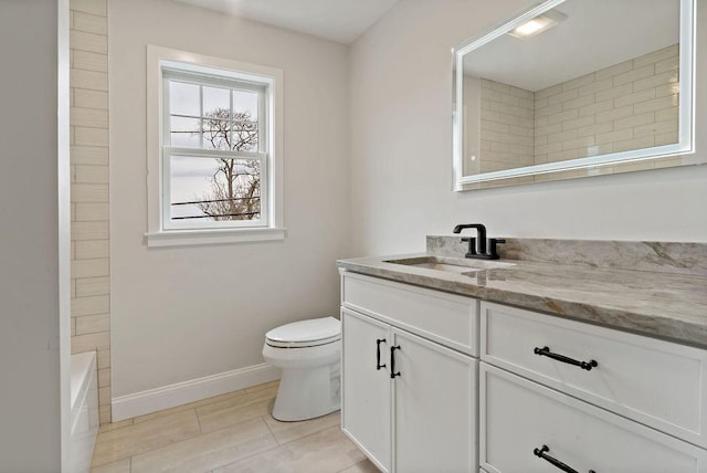 bathroom with toilet, vanity, and baseboards