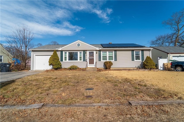 ranch-style house featuring solar panels, aphalt driveway, an attached garage, and a front lawn