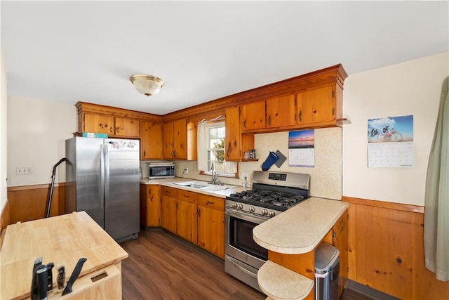 kitchen with a sink, stainless steel appliances, wainscoting, and light countertops