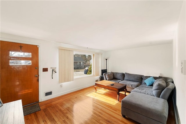 living area featuring light wood-style flooring, baseboards, visible vents, and a wealth of natural light