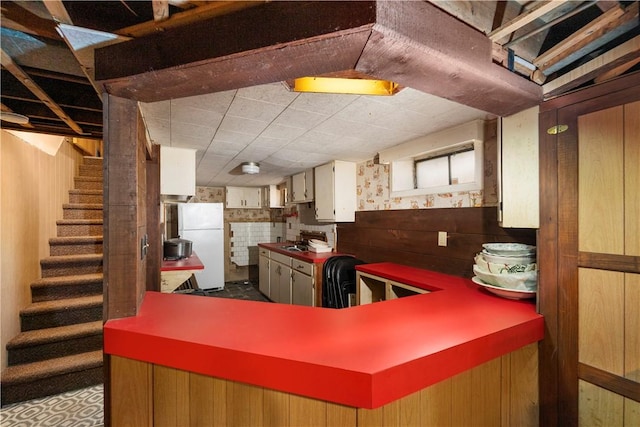 kitchen with wooden walls, freestanding refrigerator, and a sink