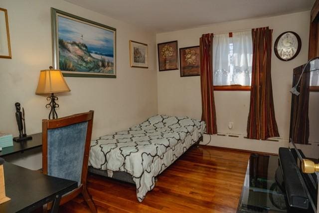 bedroom featuring a baseboard heating unit and wood finished floors