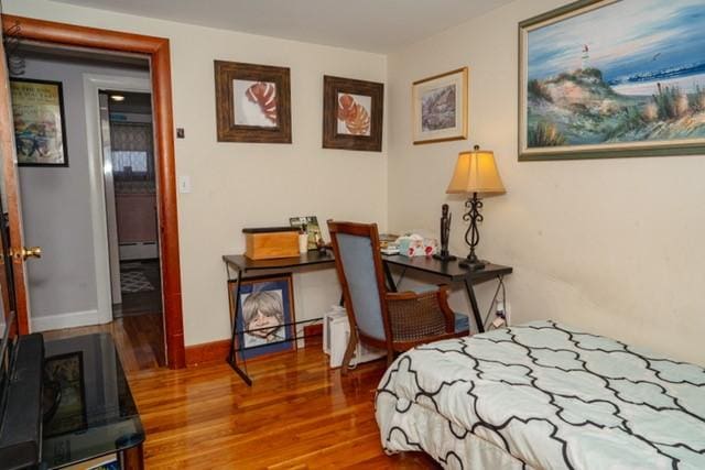 bedroom featuring baseboards, a baseboard heating unit, and wood finished floors