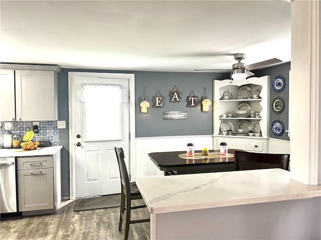 kitchen featuring decorative backsplash, ceiling fan, wood finished floors, dishwasher, and gray cabinetry