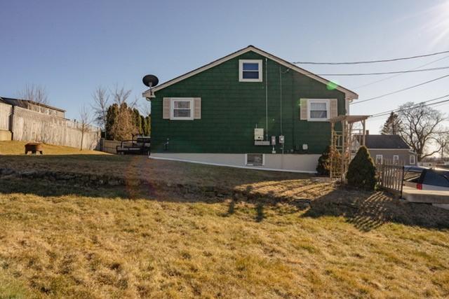 rear view of property with fence and a lawn